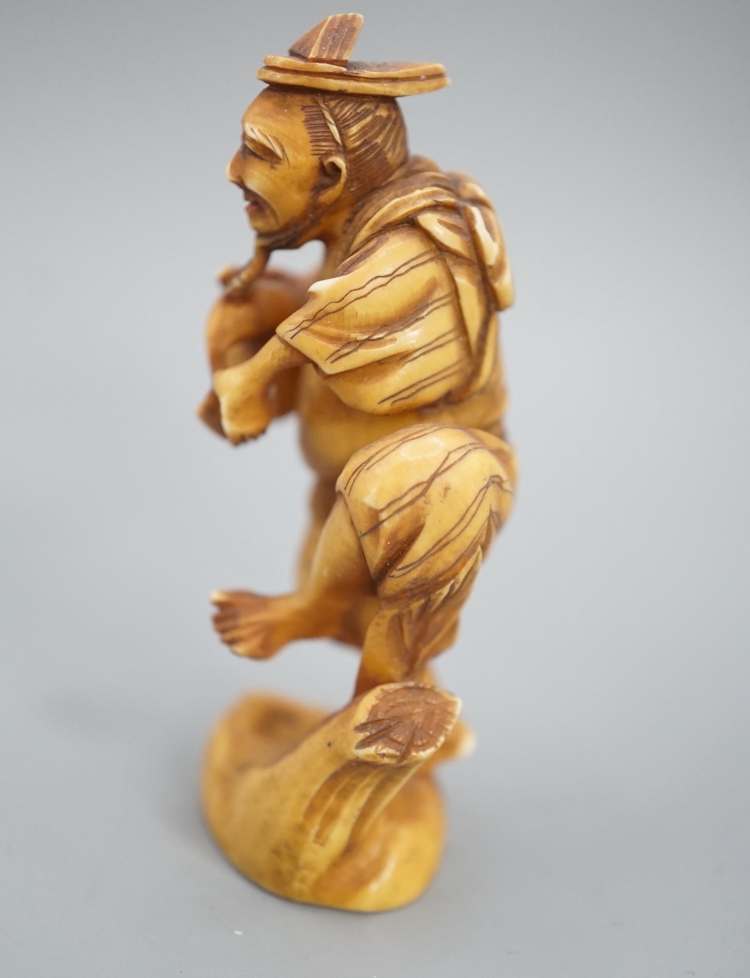 A Japanese ivory okimono of a man dancing and pouring wine from a flask, signed, Meiji period, 7cm